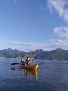 two people are in a kayak on a lake at Mai Chau Hideaway Lake Resort in Mai Châu