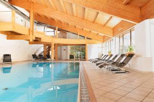 a swimming pool with chairs and a wooden ceiling at Vegan Hotel La Vimea in Naturno