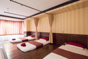 The Imperial Hotel & Convention Centre Phitsanulok في بيتسانولوك: ثلاثة أسرة في غرفة مع أرضيات خشبية وستائر