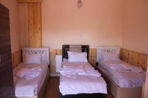 two beds in a room with white sheets at Sultan Pansion Bird Paradise in Ovaciftlik