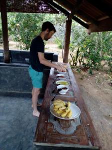 un uomo in piedi a un tavolo con piatti di banane di Taragala Chalets a Kalametiya