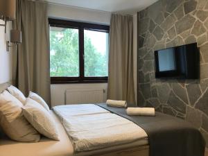 - une chambre avec un lit et une télévision murale à écran plat dans l'établissement Apartmán Lomnička - Tatranská Lomnica, à Tatranská Lomnica