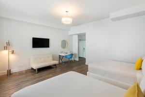Cette chambre blanche comprend un lit et une chaise. dans l'établissement President Villa, à Miami Beach