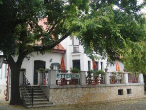 a white building with a fence and a tree at Sághegy Fogadó és Panzió in Celldömölk