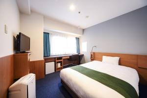 een hotelkamer met een bed, een bureau en een televisie bij Osaka Garden Palace in Osaka