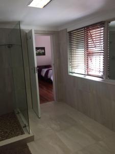 a bathroom with a bed and a window at At Sta-Plus Guest House in Port Elizabeth