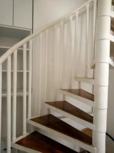 una escalera de caracol blanca con suelo de madera en una casa en Pensiunea Geostar 2 en Curtea de Argeş