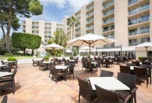 an outdoor patio with tables and chairs and umbrellas at Grupotel Orient in Playa de Palma