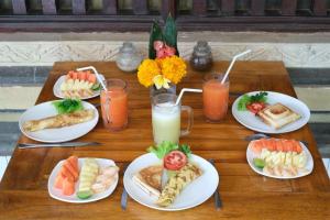 une table en bois avec des assiettes de nourriture et de boissons dans l'établissement Kabera House 2, à Ubud