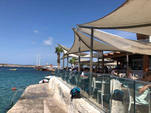 um grupo de pessoas sentadas em um restaurante ao lado da água em Mellieha Bay Waters Edge No. 160 em Mellieha