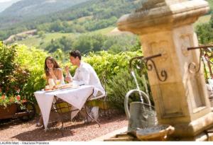 a man and woman sitting at a table with wine glasses at Le Clos des Evigneaux in Rasteau