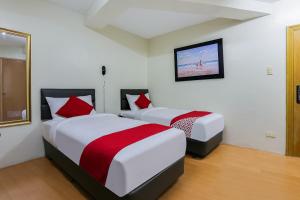 two beds in a hotel room with a tv at OYO 190 Anglo Residences in Manila