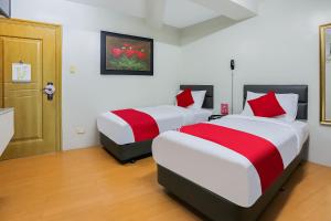 a bedroom with two beds with red and white sheets at OYO 190 Anglo Residences in Manila