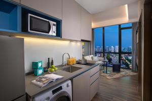 a kitchen with a sink and a microwave above a dishwasher at Citadines Balestier in Singapore