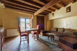 Una sala de estar con un sofá, una mesa y sillas. en Palacio Conde de Cabra, en Granada