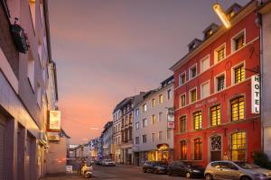 a city street with buildings and a person on a scooter at Novum Hotel Ahl Meerkatzen Köln Altstadt in Cologne