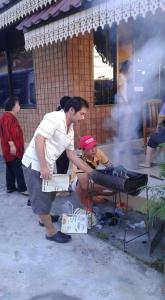 a man is cooking food on a grill at สุขทวีรีสอร์ท อ่าวมะนาว in Prachuap Khiri Khan