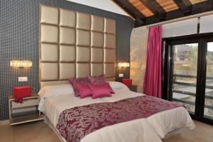 a bedroom with a large bed with pink pillows at El Balcon Del Cañon in Ucero