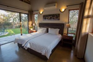 a bedroom with a large bed and a large window at Igugu Lodge in Hoedspruit +5 photos