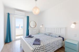 a bedroom with a bed with blue curtains and a window at Pé na Praia in Albufeira +46 photos