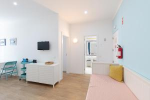 a white living room with a desk and a tv at Pé na Praia in Albufeira