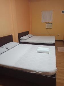 2 Betten mit weißer Bettwäsche in einem Zimmer in der Unterkunft Lagnason's Place in Oslob
