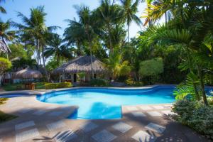 a swimming pool in a resort with palm trees at Pura Vida Beach & Dive Resort in Dauin