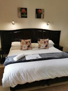 a large bed with a black head board and pillows at Victoria and Alfred Guest House in Port Elizabeth