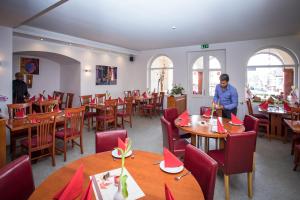 a restaurant with tables and chairs with a woman standing in the middle at Hotel Ratskeller in Nideggen