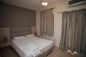 a bedroom with a white bed and a window at T'Aloni in Chortáta