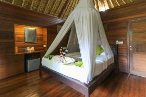 een slaapkamer met een bed met een klamboe bij Koji Garden Huts - CHSE Certified in Nusa Lembongan