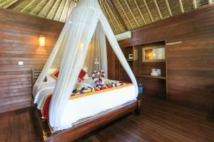 a bedroom with a bed with a canopy at Koji Garden Huts - CHSE Certified in Nusa Lembongan