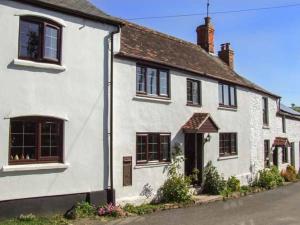 a white house with black windows on a street at Herefordshire Holiday Cottages in Lea