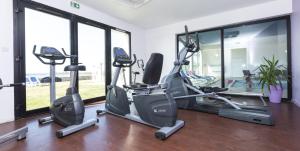 een fitnessruimte met loopbanden en crosstrainers in een kamer met ramen bij Résidence Odalys Domaine des Roches Jaunes in Plougasnou