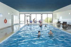 a group of people in a swimming pool at Résidence Odalys Domaine des Roches Jaunes in Plougasnou