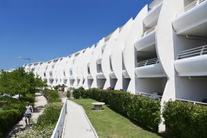 un gran edificio blanco con una acera al lado en Résidence Odalys Les Dunes du Soleil en La Grande-Motte