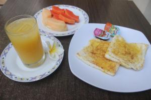 two plates of food with toast and a glass of orange juice at Loven Sanur Guest House in Sanur +21 photos