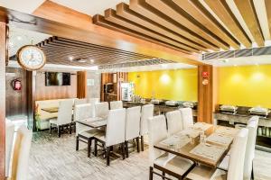 a dining room with tables and chairs and a clock at Saibala Grand Airport Hotel in Chennai