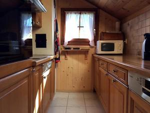 cocina con armarios de madera y microondas en Charmant Petit Chalet 3 étoiles en Gruyère en Crésuz