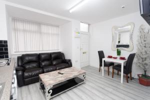 a living room with a black leather couch and a table at Calvin House Apartments in Leeds