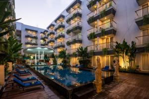 a hotel with a swimming pool in front of a building at EDEN Hotel Kuta Bali in Kuta