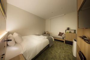 a hotel room with a white bed and a couch at Shizutetsu Hotel Prezio Kyoto Shijo in Kyoto
