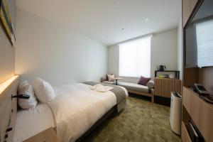 a hotel room with a bed and a couch at Shizutetsu Hotel Prezio Kyoto Shijo in Kyoto