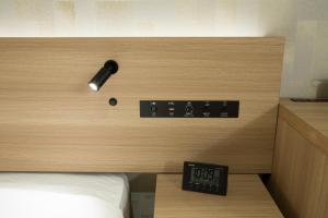a room with a bed and an alarm clock on the wall at Shizutetsu Hotel Prezio Kyoto Shijo in Kyoto