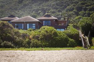 a house sitting on top of a hill next to the water at Archrock Resort in Plettenberg Bay