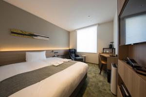 a hotel room with a large bed and a desk at Shizutetsu Hotel Prezio Kyoto Shijo in Kyoto
