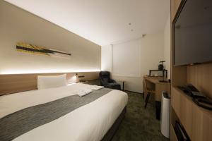 a hotel room with a large bed and a desk at Shizutetsu Hotel Prezio Kyoto Shijo in Kyoto