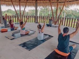 um grupo de pessoas sentadas em uma aula de yoga em Coco Verde Bali Resort em Tanah Lot