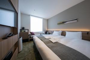 a hotel room with a large bed and a flat screen tv at Shizutetsu Hotel Prezio Kyoto Shijo in Kyoto
