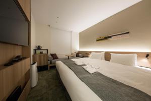 a hotel room with a large bed and a flat screen tv at Shizutetsu Hotel Prezio Kyoto Shijo in Kyoto